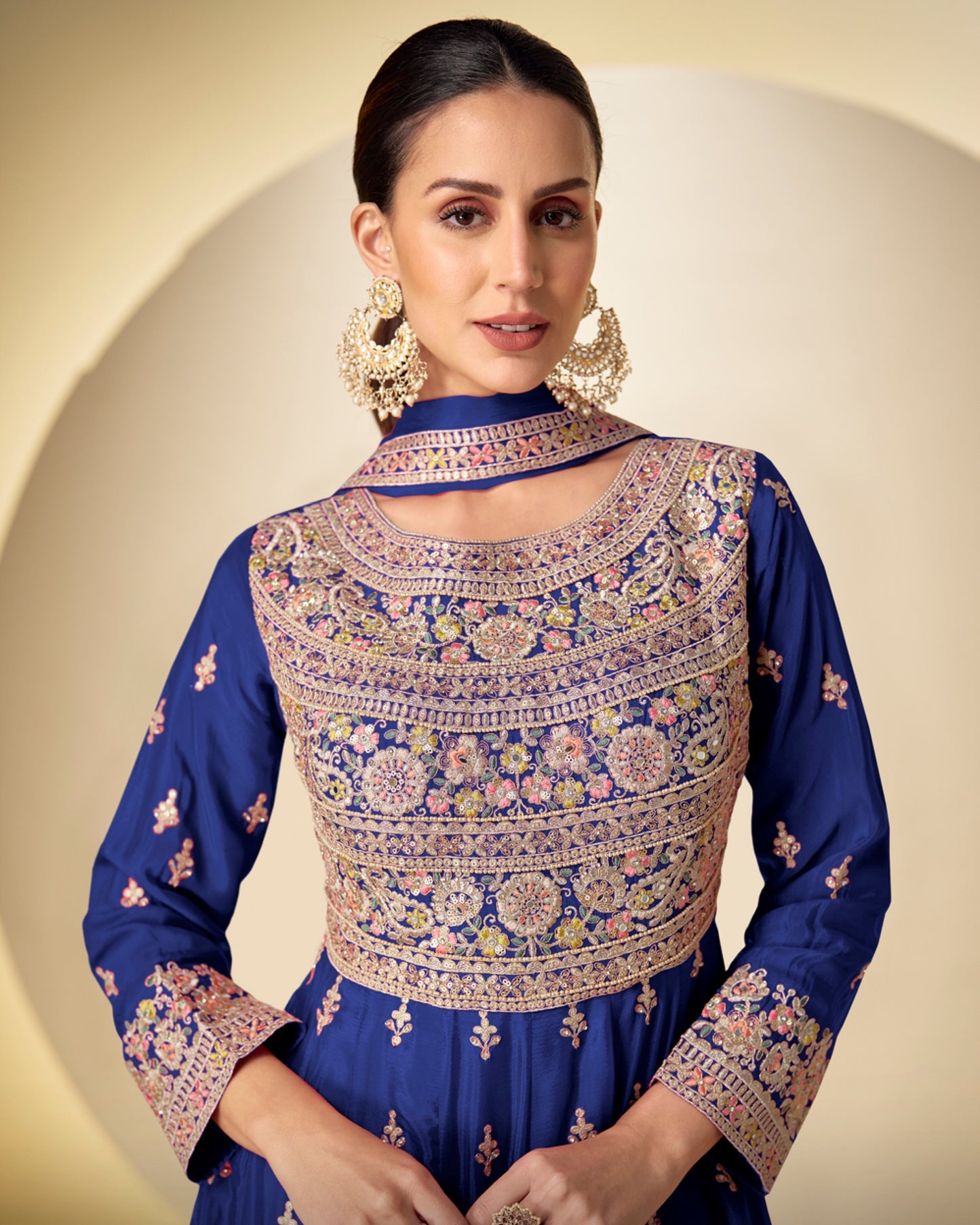 Woman wearing a blue embroidered traditional outfit with a beige background