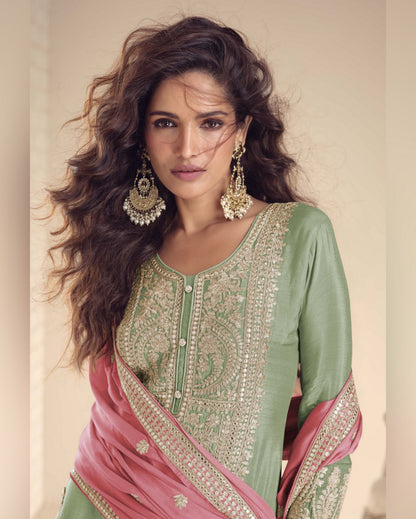 Woman wearing a green and pink traditional outfit with jewelry against a neutral background