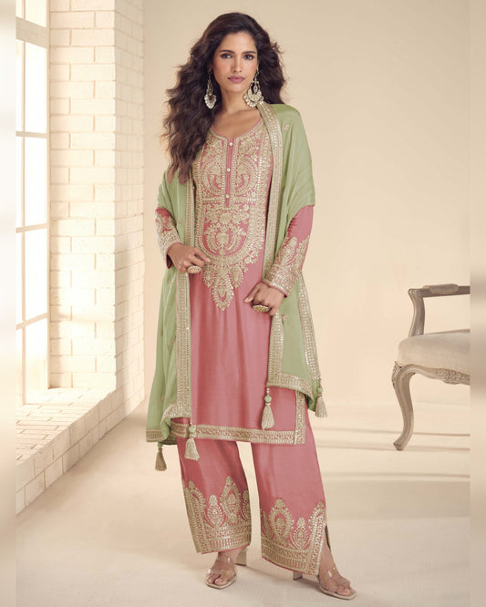 Woman wearing a pink and green traditional outfit in a bright room.