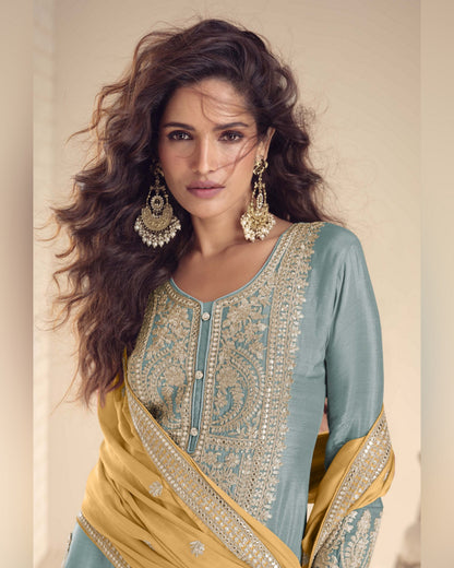 Woman wearing a traditional outfit with intricate patterns and jewelry against a neutral background