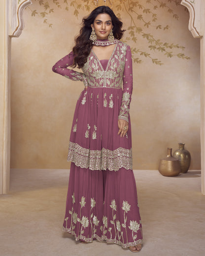 Woman wearing a purple embroidered traditional outfit in a decorated room.
