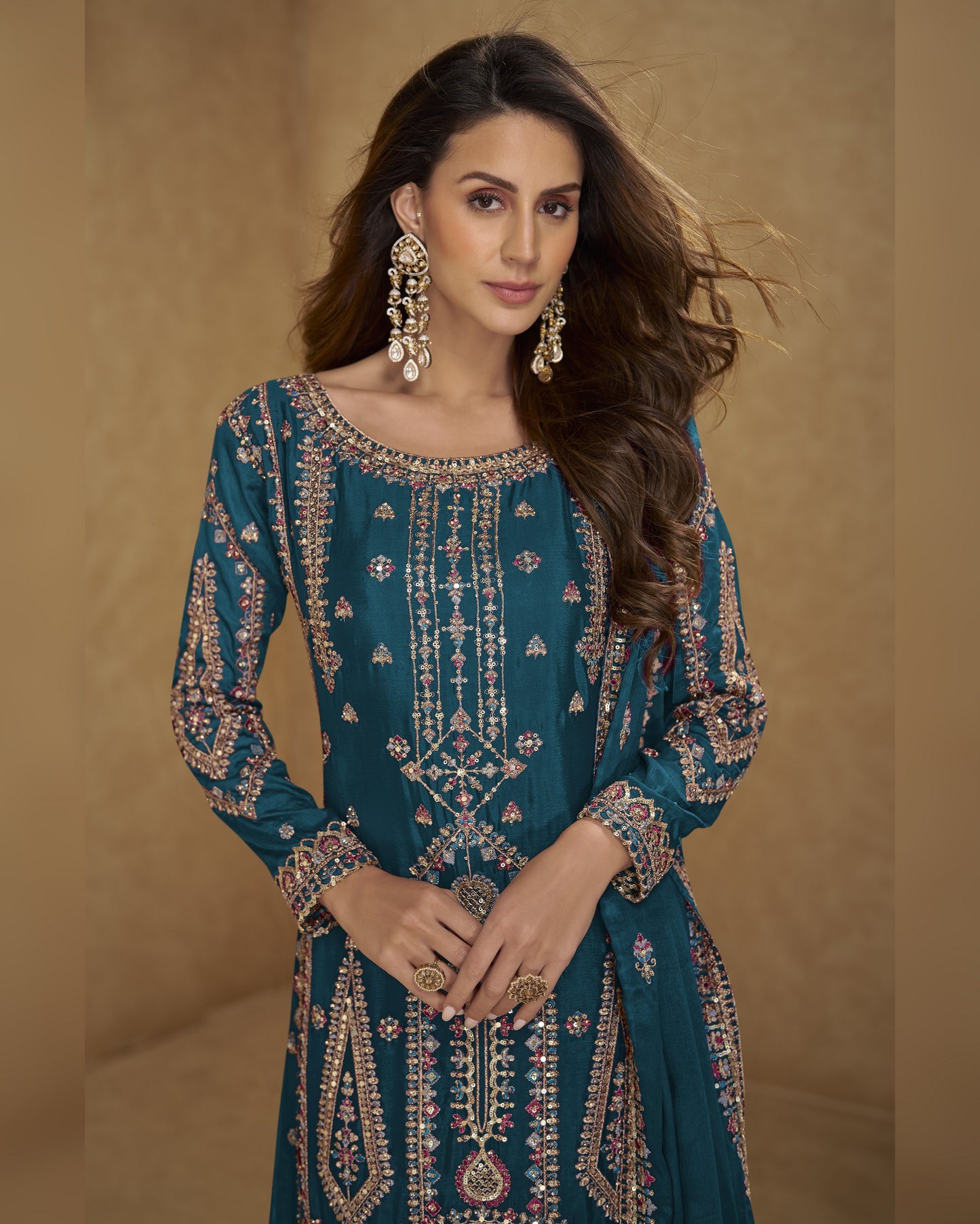 Woman wearing a teal embroidered dress with a beige background