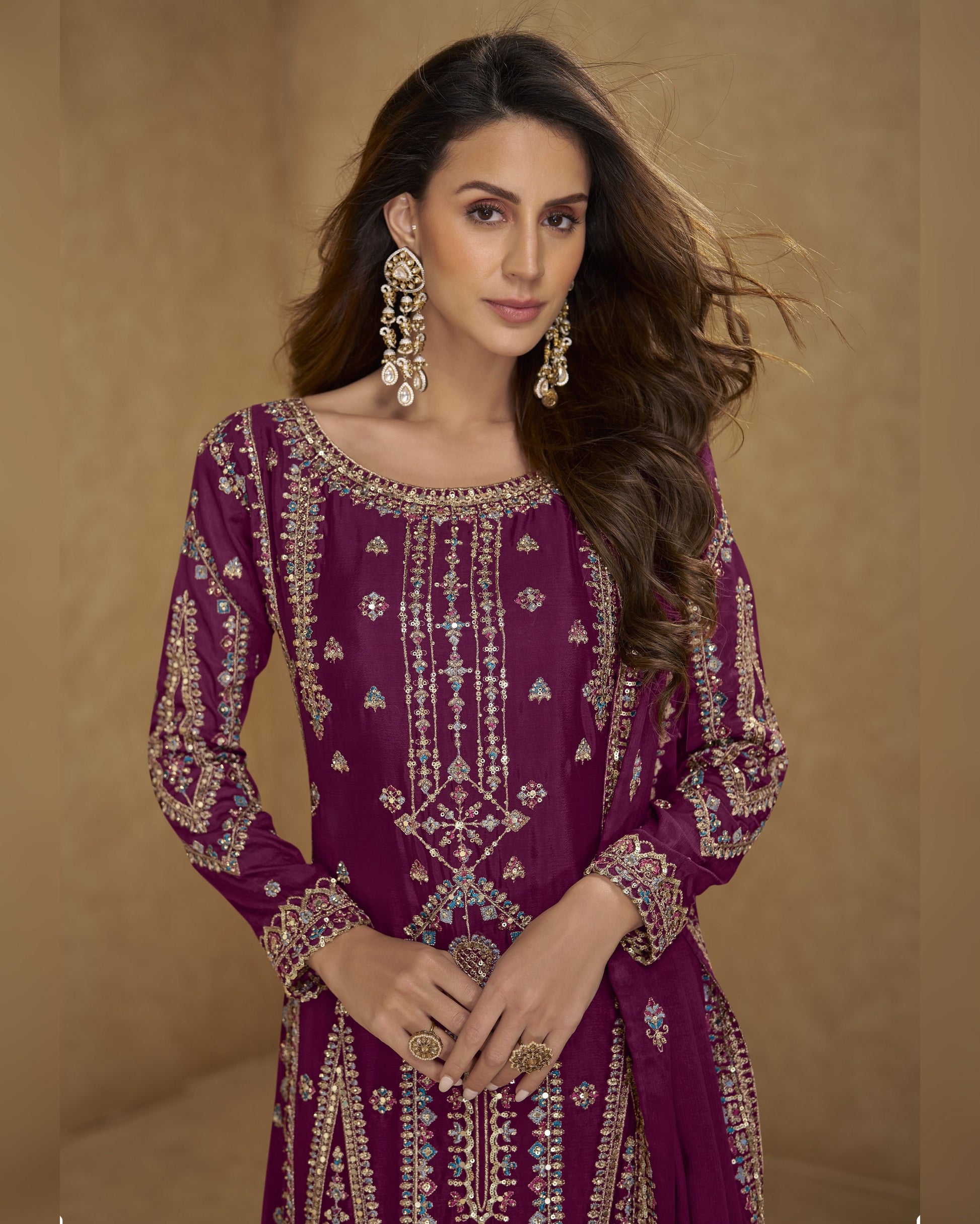 Woman wearing a purple embroidered outfit with gold details on a beige background