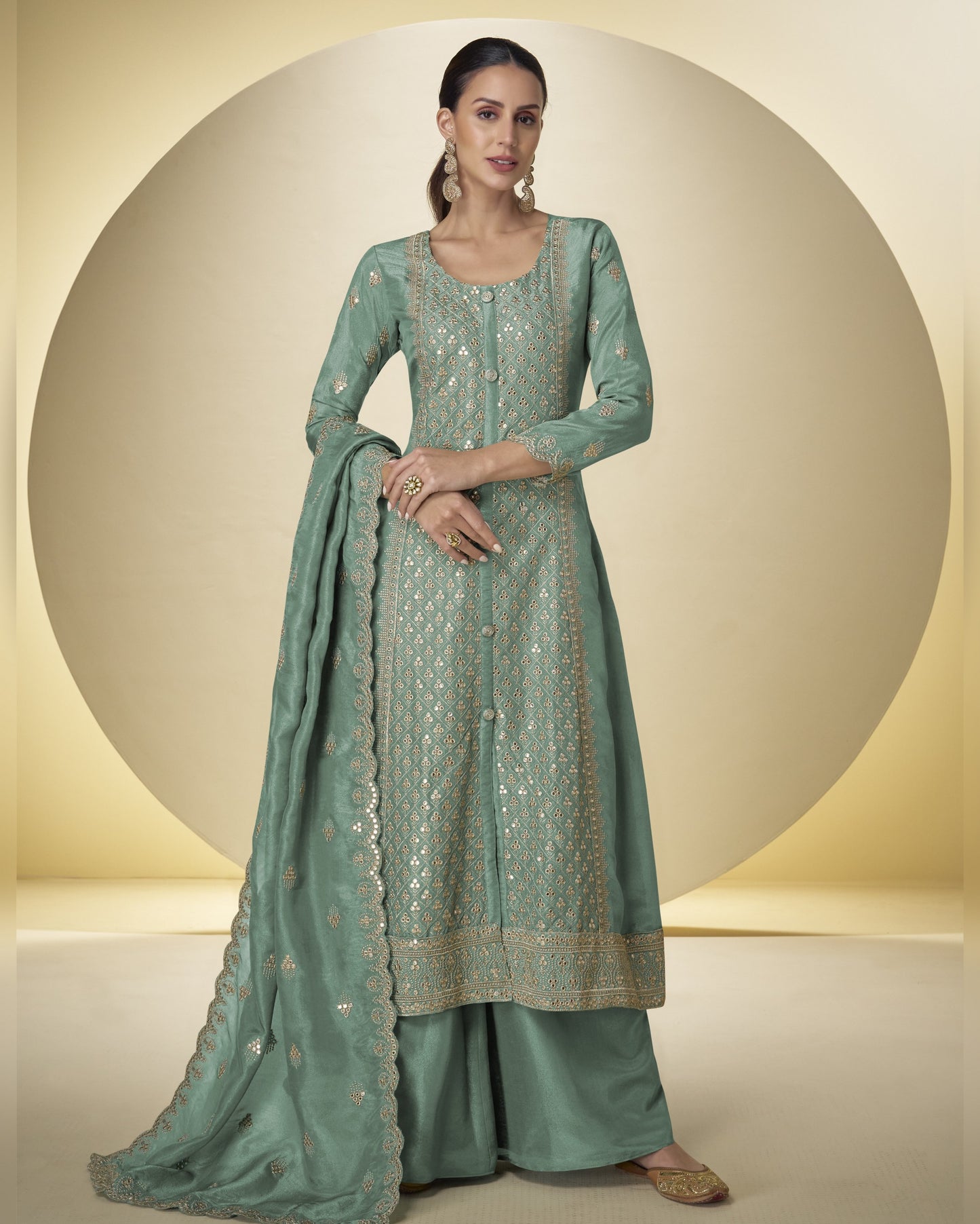 Woman wearing a light green traditional outfit with intricate patterns on a neutral background