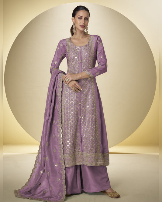 Woman wearing a purple embroidered traditional outfit with a matching dupatta on a beige background