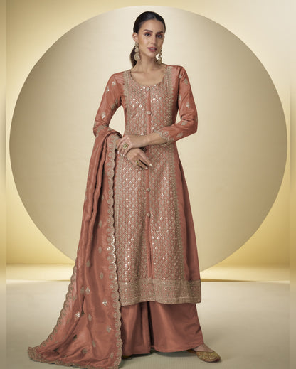 Woman wearing a traditional embroidered pink outfit with a matching dupatta on a beige background