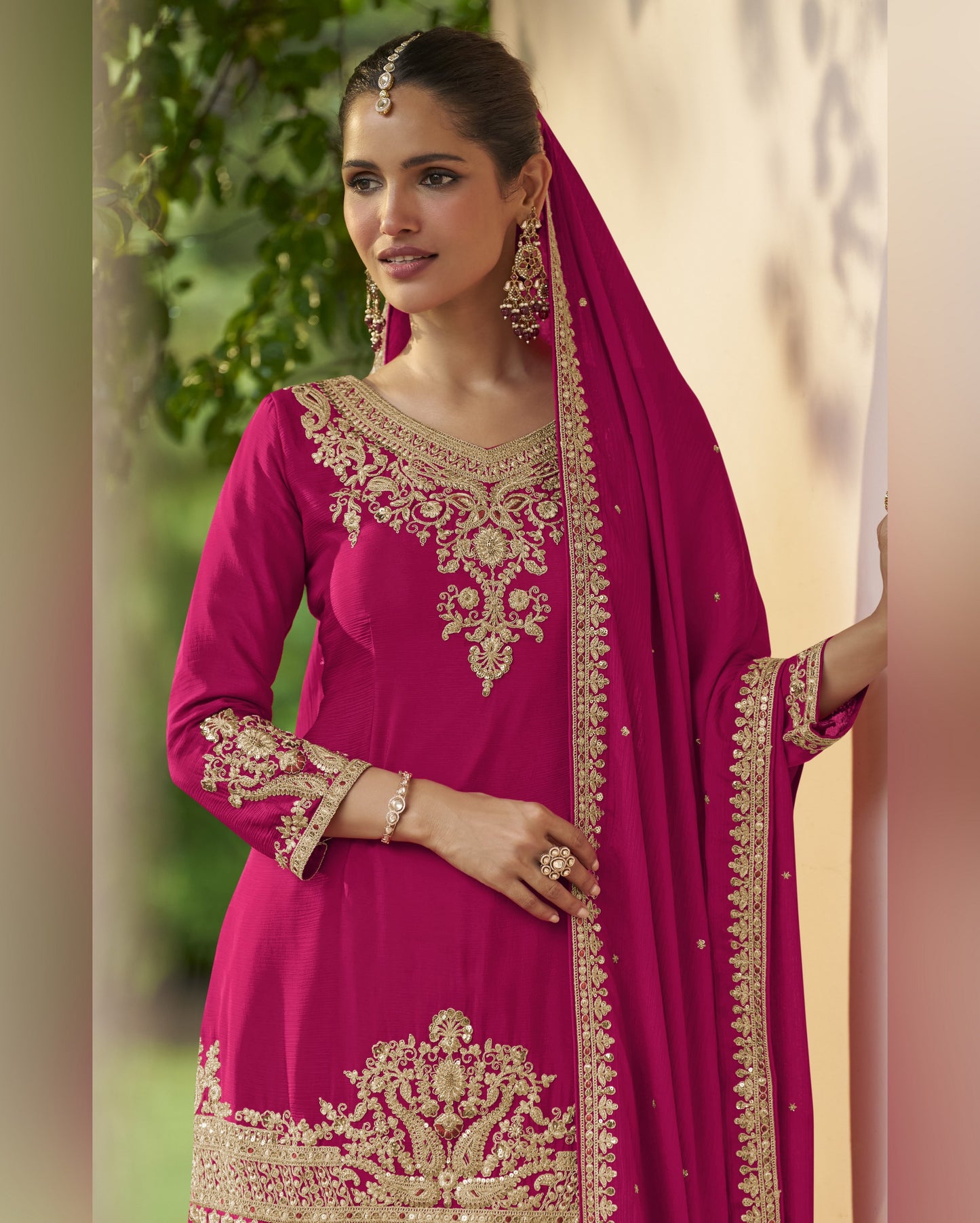 Woman wearing a pink embroidered traditional outfit with a beige background