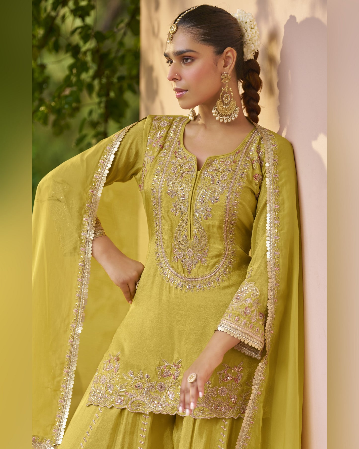 Woman wearing a green embroidered traditional outfit with a blurred natural background