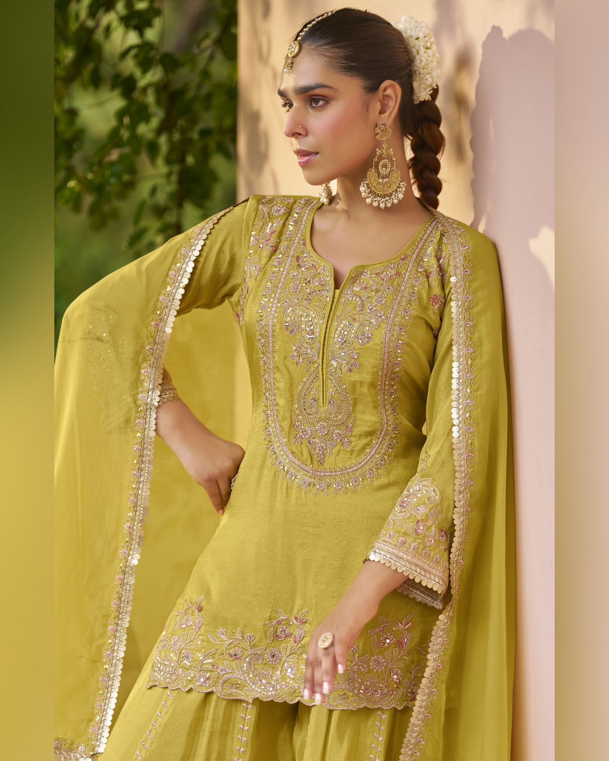 Woman wearing a green embroidered traditional outfit with a blurred natural background
