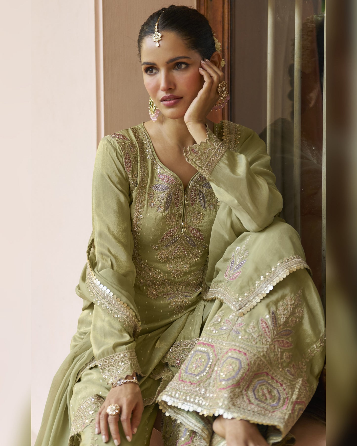 Woman in a traditional embroidered outfit sitting indoors.