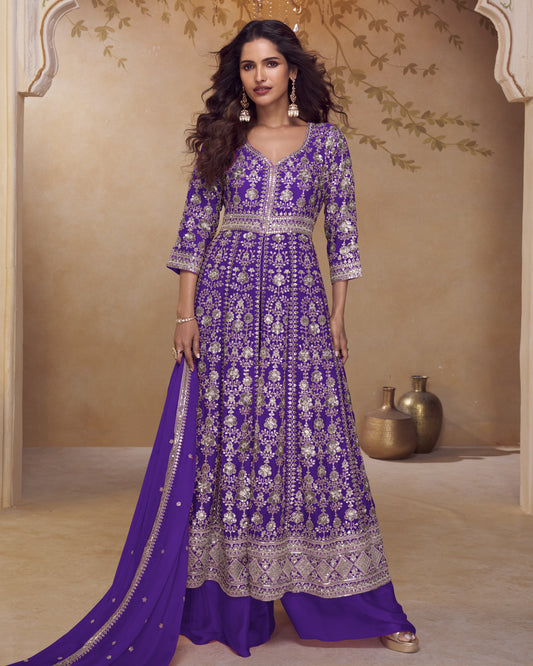 Woman wearing a purple embroidered traditional outfit in a decorated room.