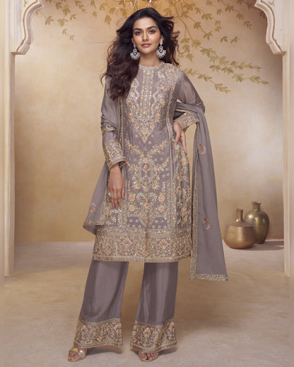 Woman in a traditional outfit with intricate patterns in a decorated room.