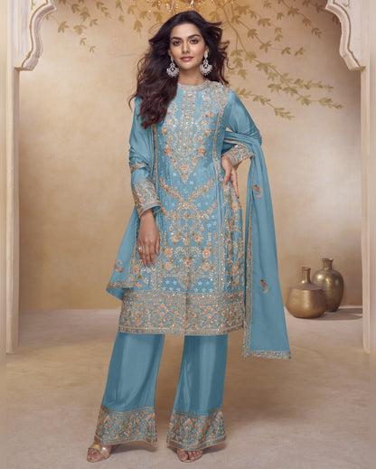 Woman wearing a light blue embroidered traditional outfit with a beige background