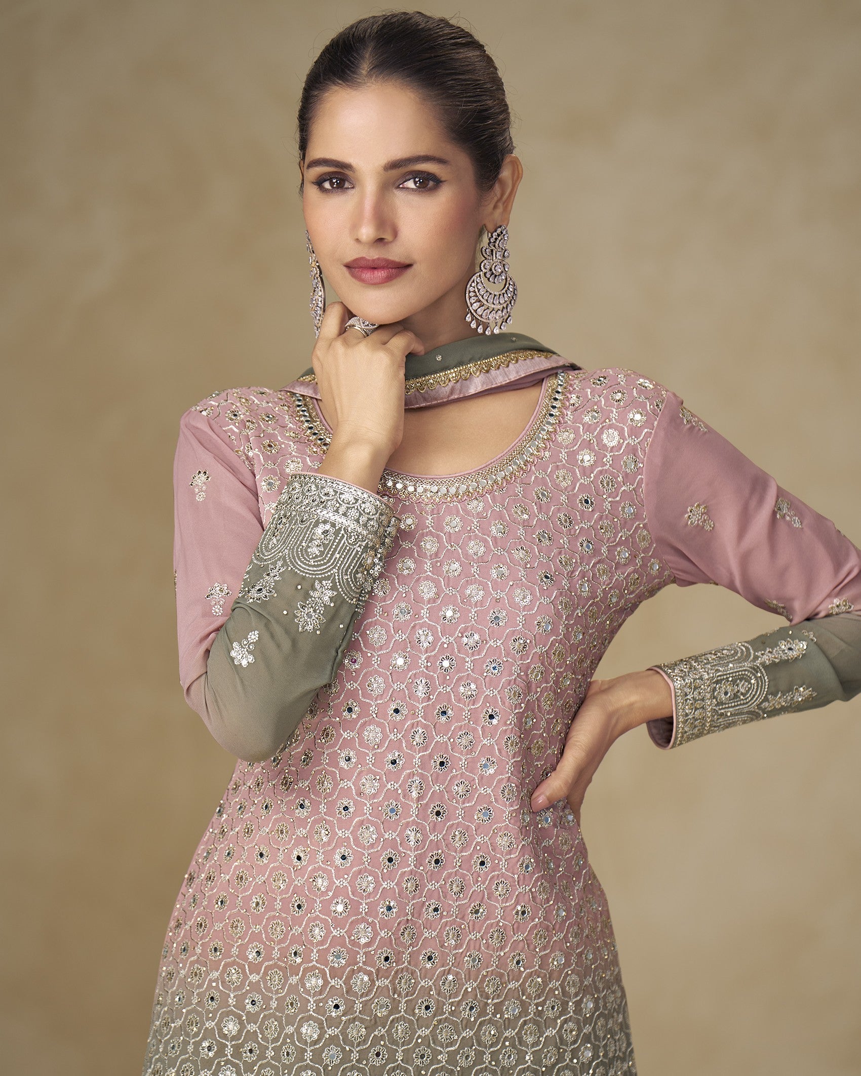 Woman wearing a pink and gray embroidered traditional outfit against a beige background