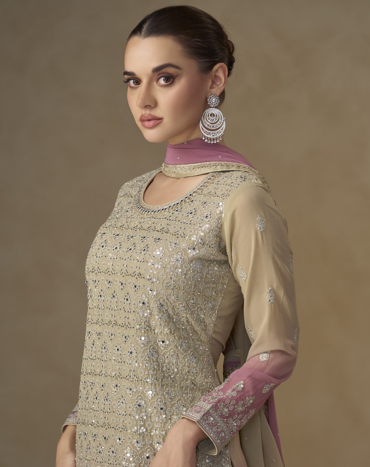 Woman wearing a traditional outfit with intricate designs on a beige background