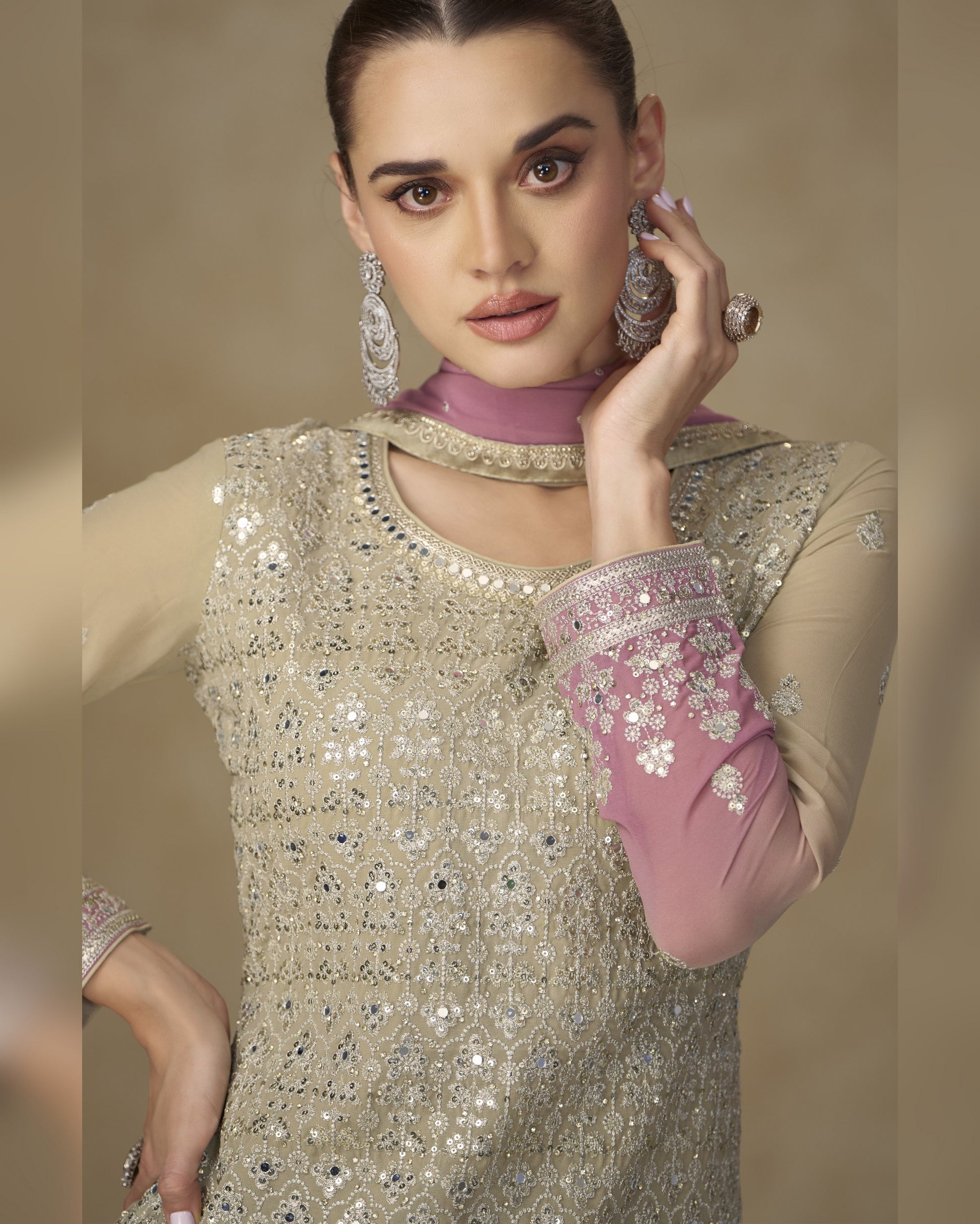 Woman wearing a beaded and embroidered outfit with jewelry on a beige background