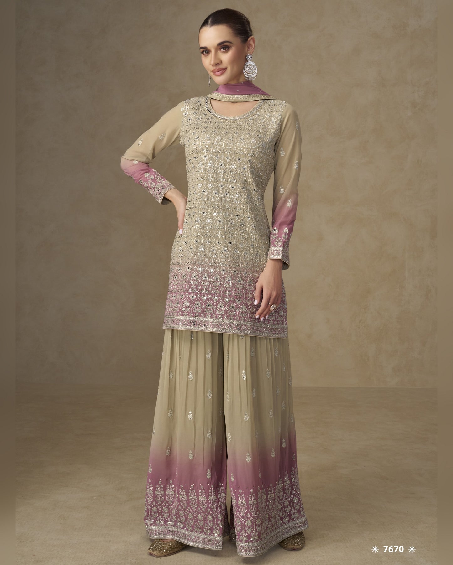 Woman wearing a traditional outfit with a beige and pink patterned top and matching palazzo pants on a brown background.