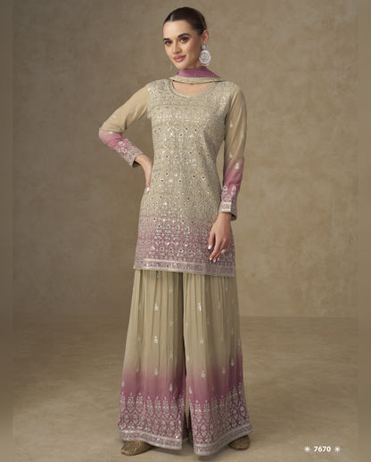 Woman wearing a traditional outfit with a beige and pink patterned top and matching palazzo pants on a brown background.