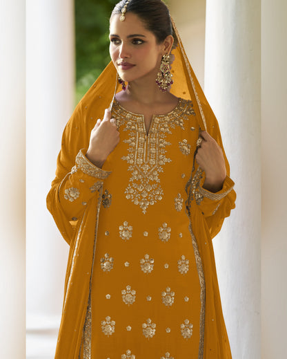 Woman wearing a mustard yellow embroidered traditional outfit with a dupatta.