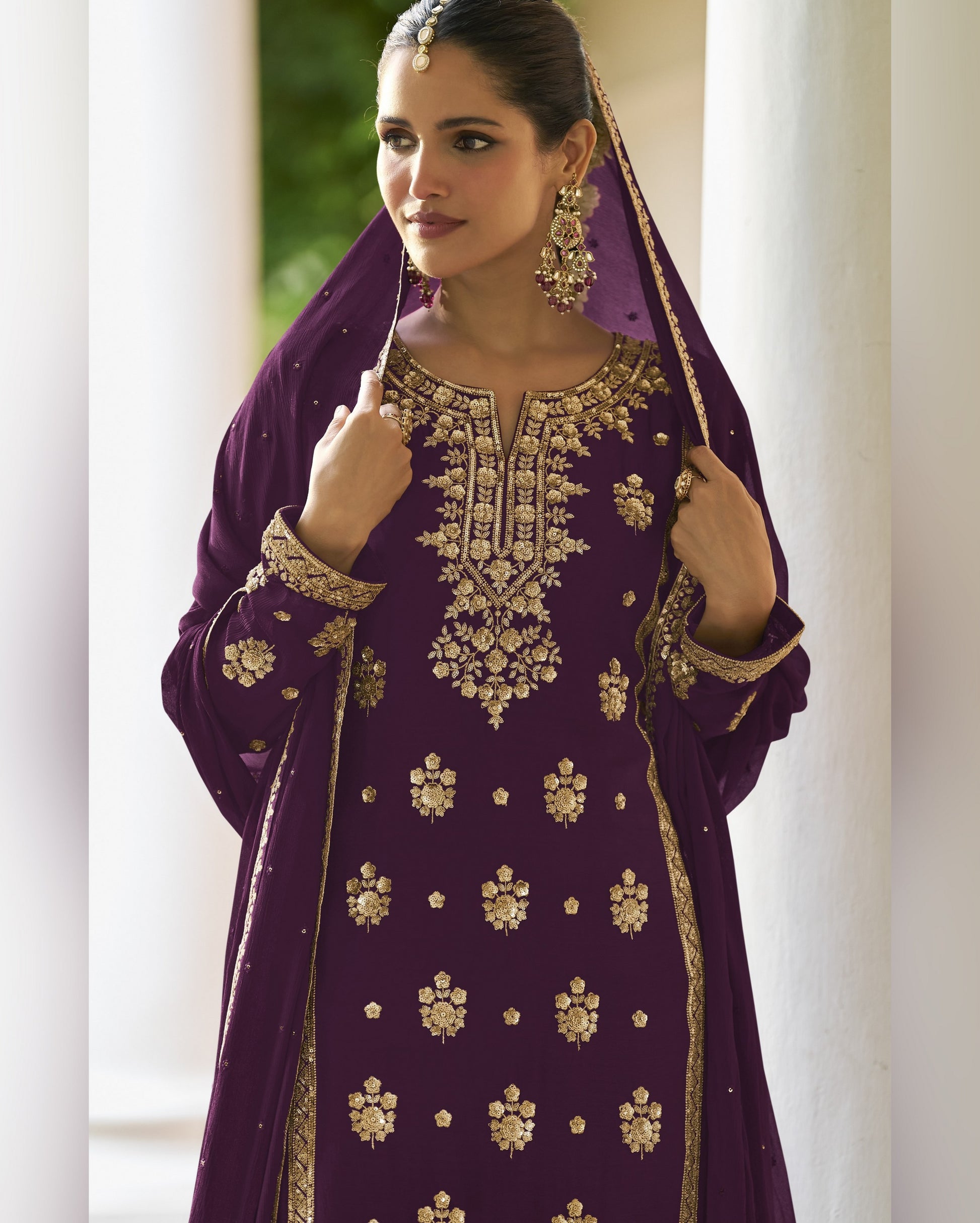 Woman wearing a purple embroidered traditional outfit with gold details.