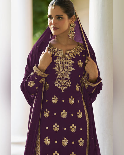 Woman wearing a purple embroidered traditional outfit with gold details.