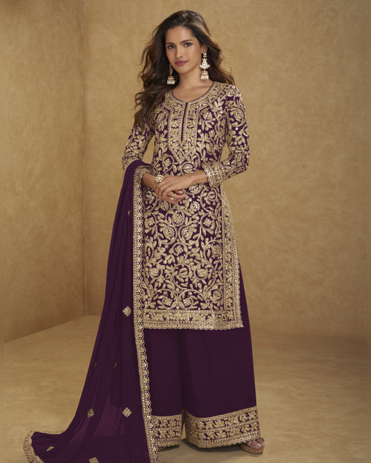 Woman wearing a traditional embroidered outfit with a purple dupatta against a beige background