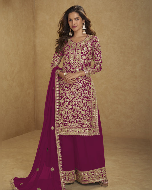 Woman wearing a traditional embroidered outfit with a pink dupatta on a beige background