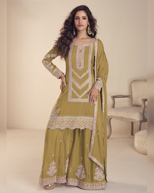 Woman wearing a green embroidered traditional outfit in a neutral setting