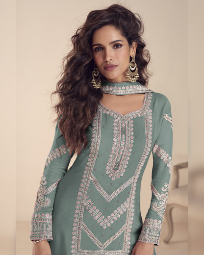 Woman wearing a green embroidered traditional outfit with a neutral background
