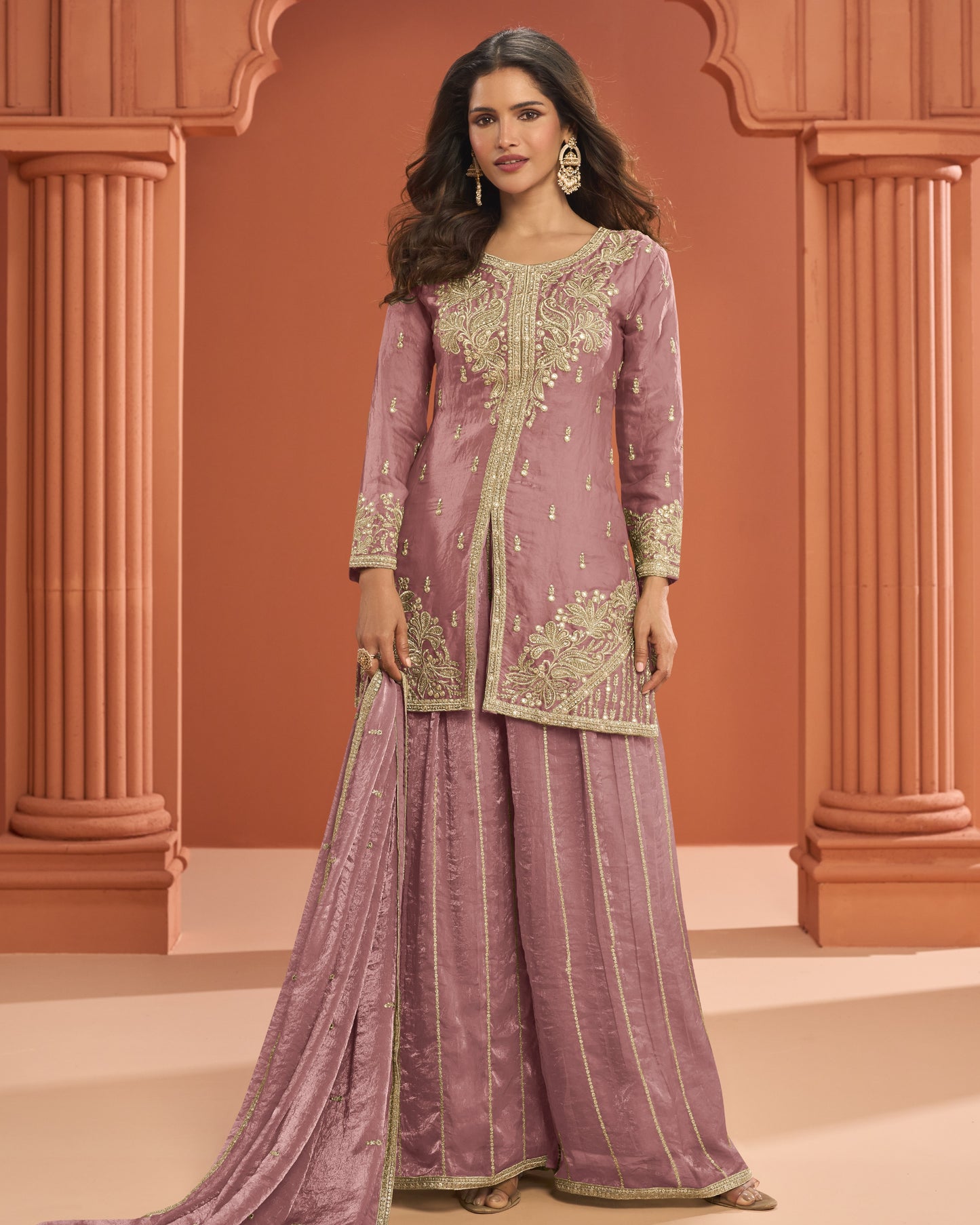 Woman wearing a traditional outfit with intricate embroidery against an architectural background