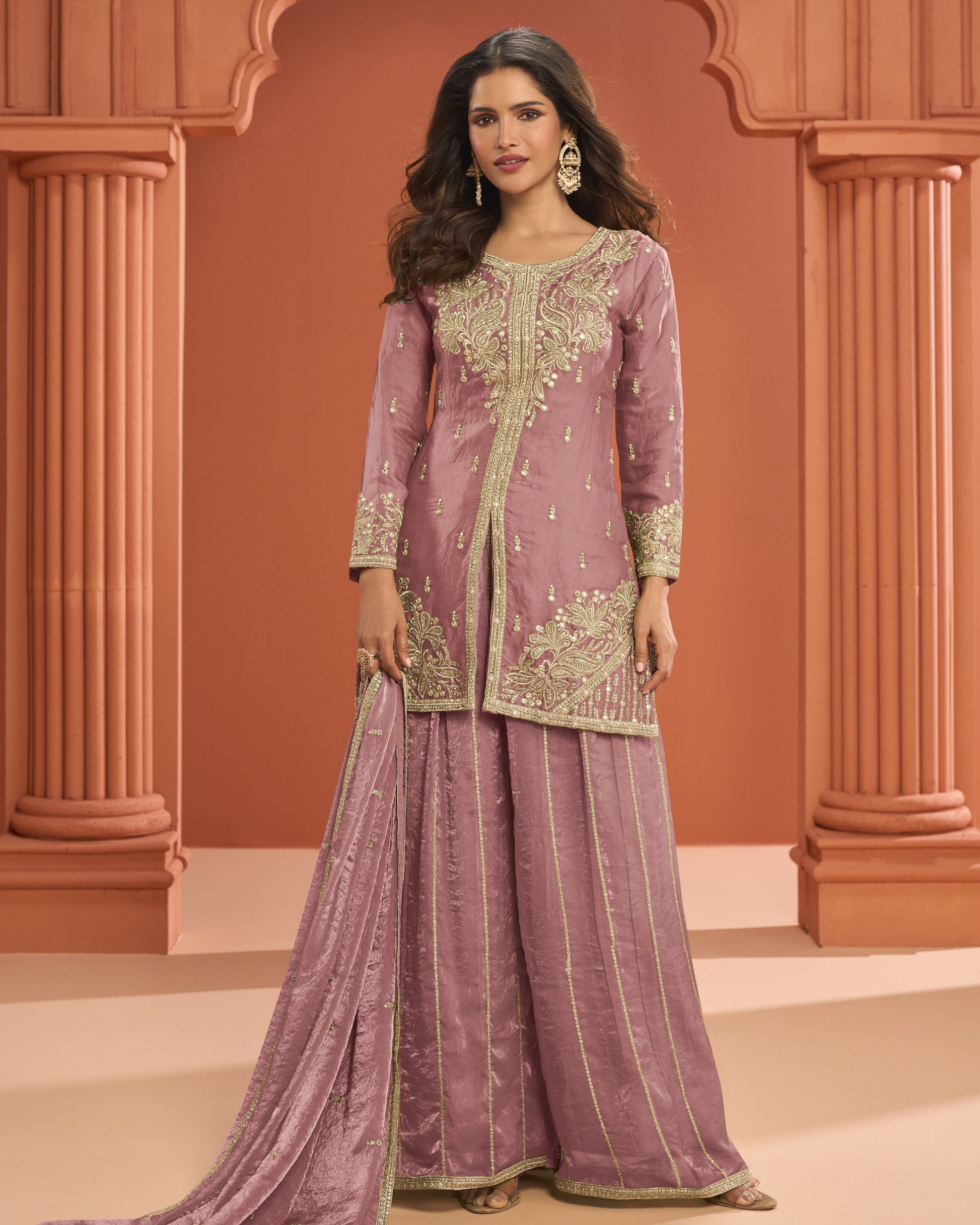 Woman wearing a traditional outfit with intricate embroidery against an architectural background