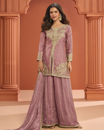 Woman wearing a traditional outfit with intricate embroidery against an architectural background