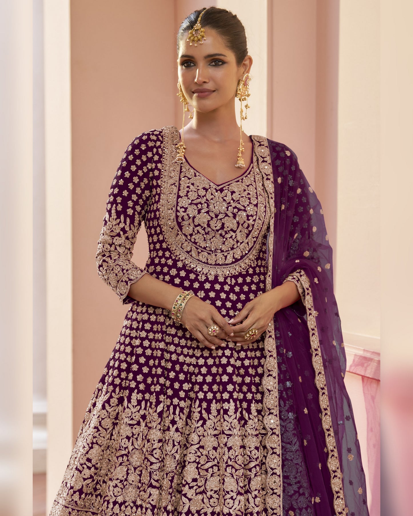 Woman wearing a traditional purple and gold embroidered outfit with a dupatta.