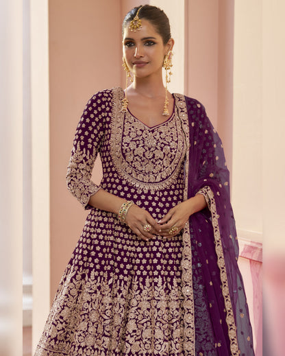 Woman wearing a traditional purple and gold embroidered outfit with a dupatta.