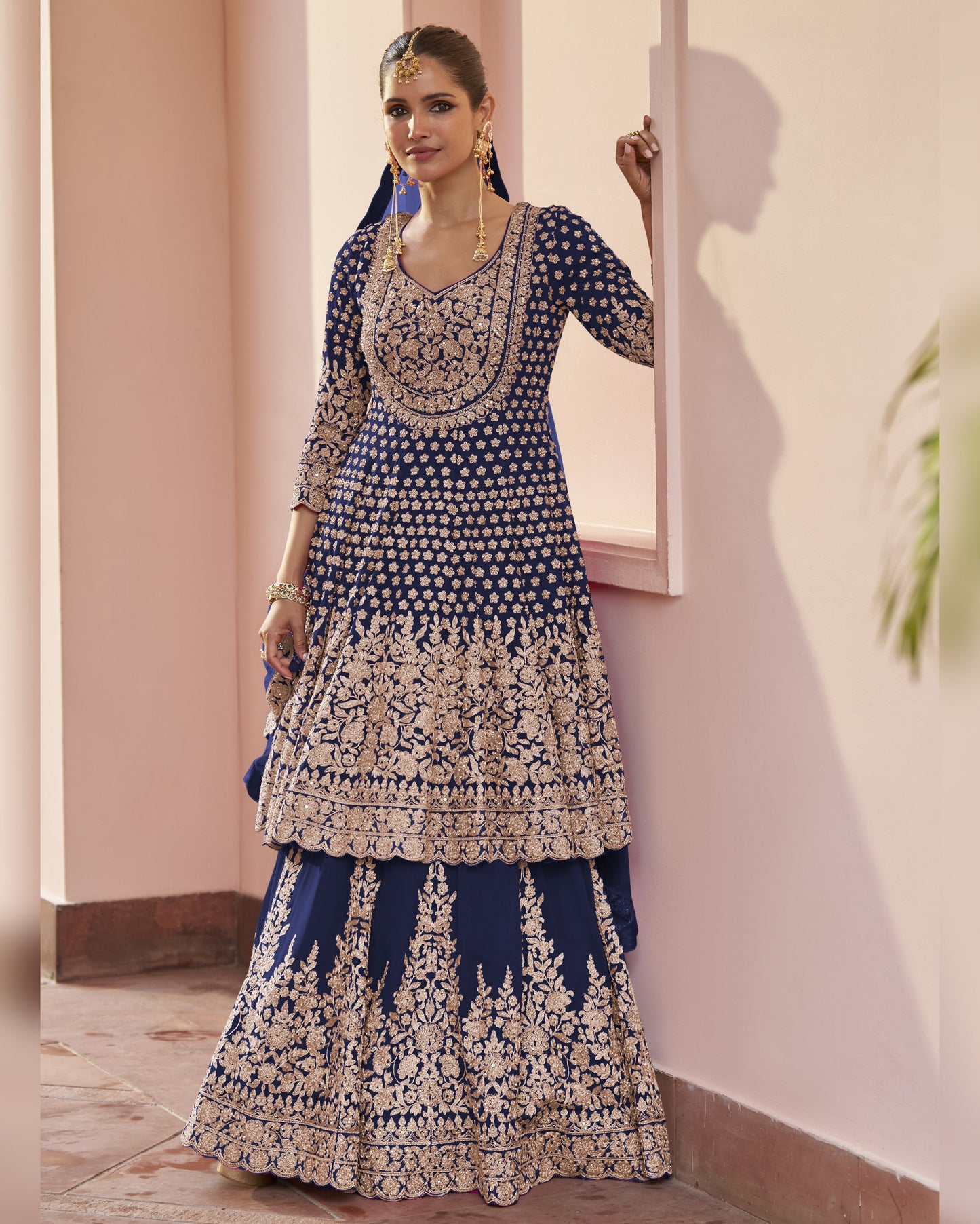 Woman wearing a blue and white embroidered traditional outfit indoors.