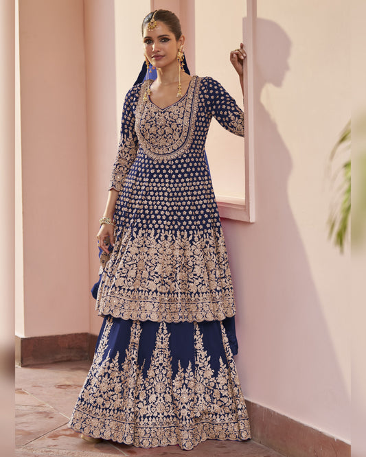 Woman wearing a blue and white embroidered traditional outfit indoors.