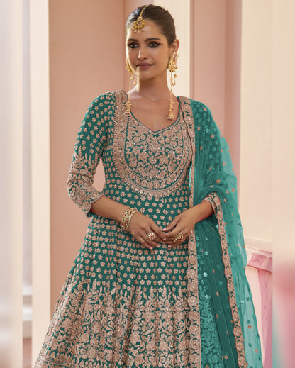 Woman wearing a teal and gold embroidered traditional outfit with a matching dupatta.