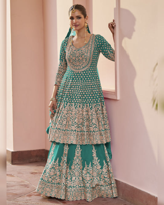 Woman wearing a green and white embroidered traditional outfit indoors.