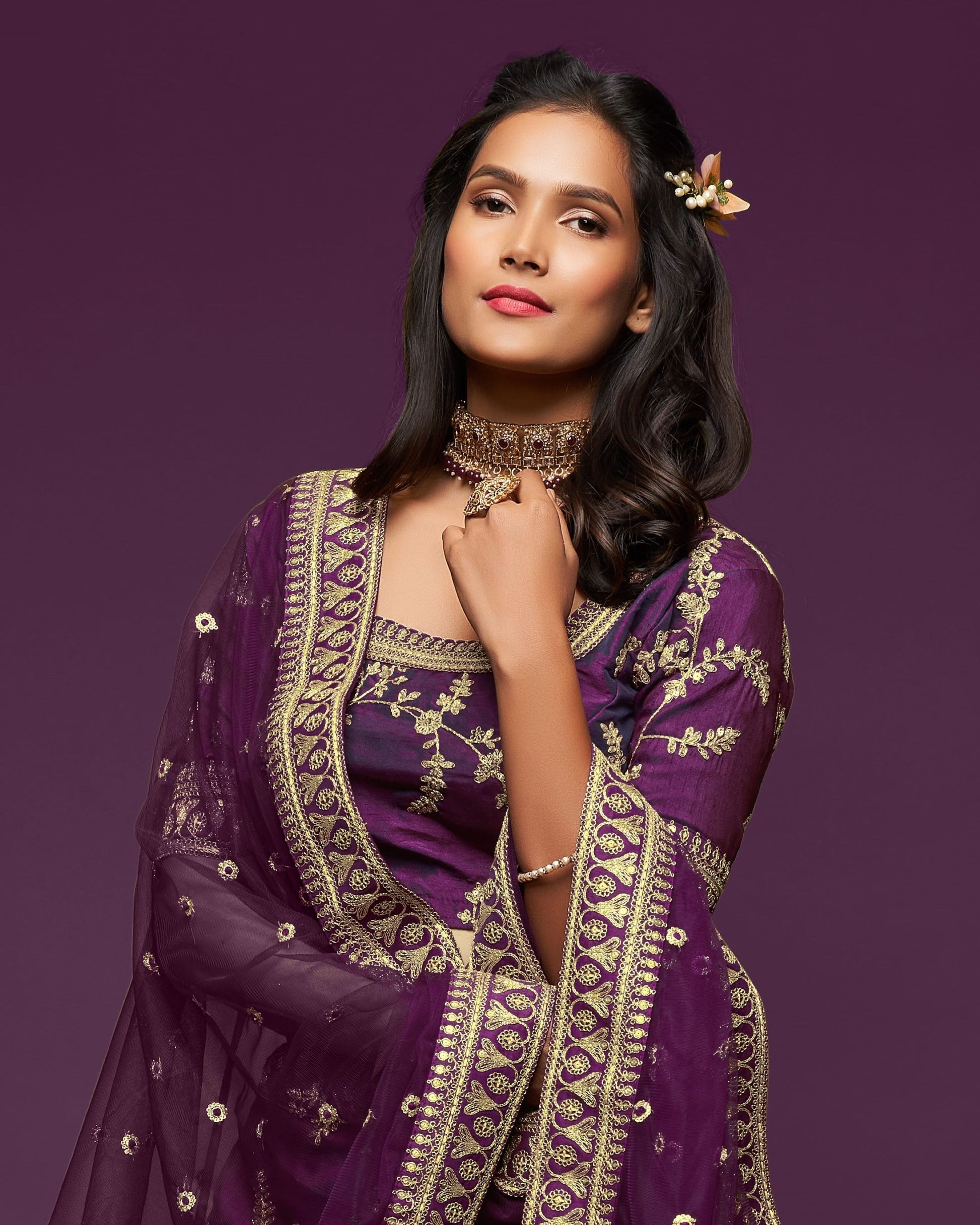 Woman wearing a purple embroidered traditional outfit against a purple background
