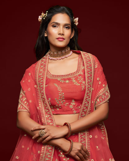 Woman in a red embroidered traditional outfit with jewelry against a dark red background