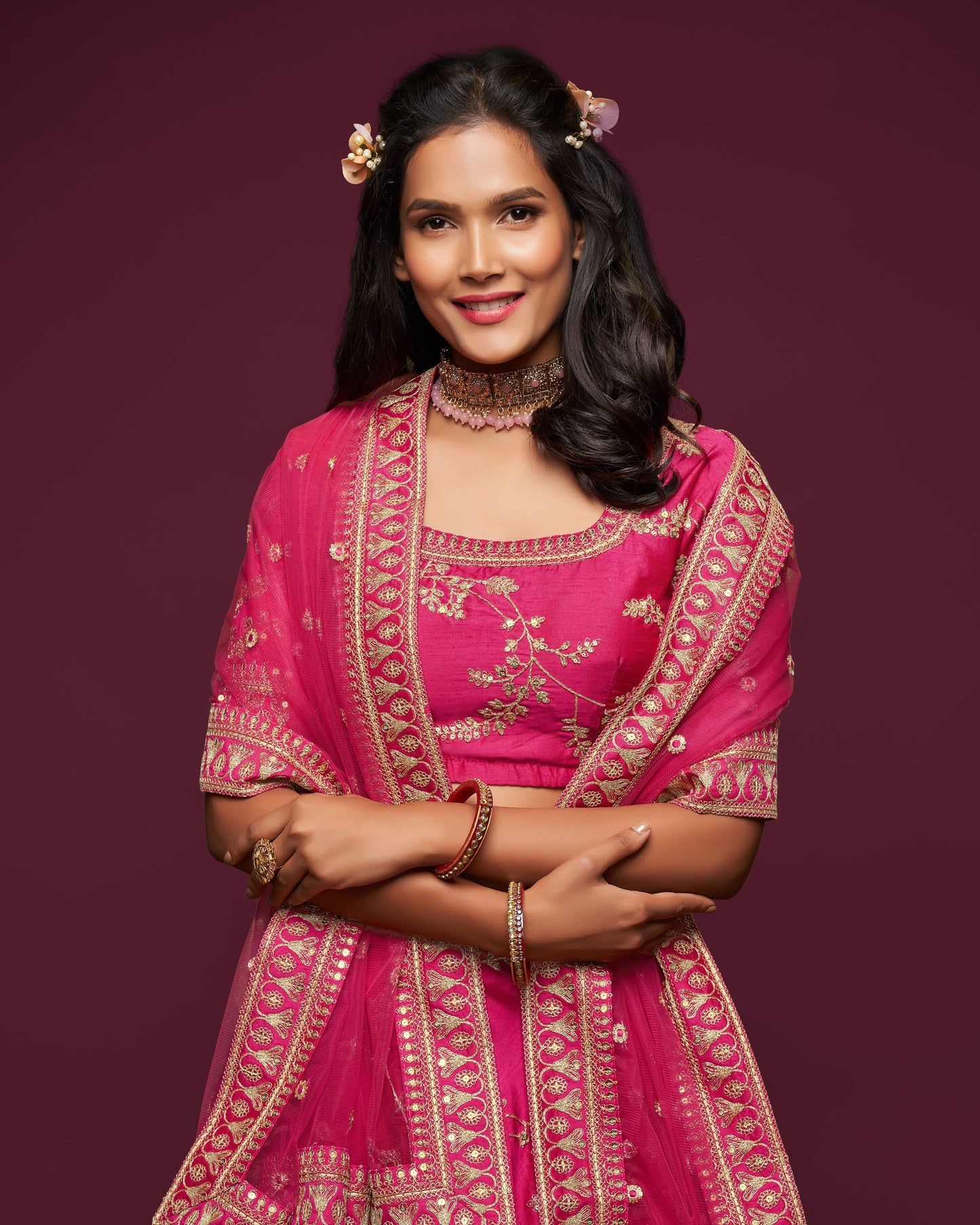 Woman wearing a pink traditional outfit with gold embroidery on a dark purple background