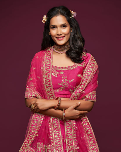 Woman wearing a pink traditional outfit with gold embroidery on a dark purple background