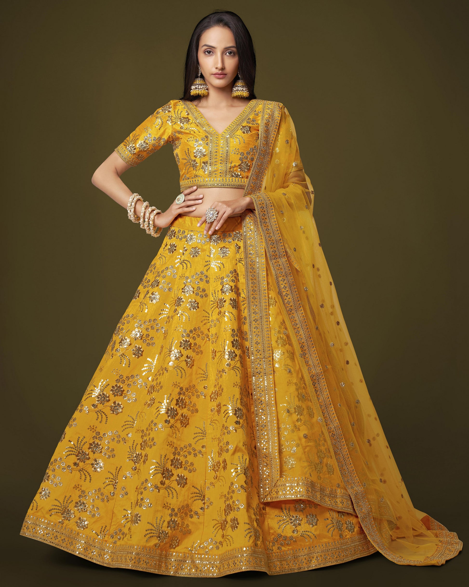 Woman wearing a yellow embroidered traditional outfit on a dark background