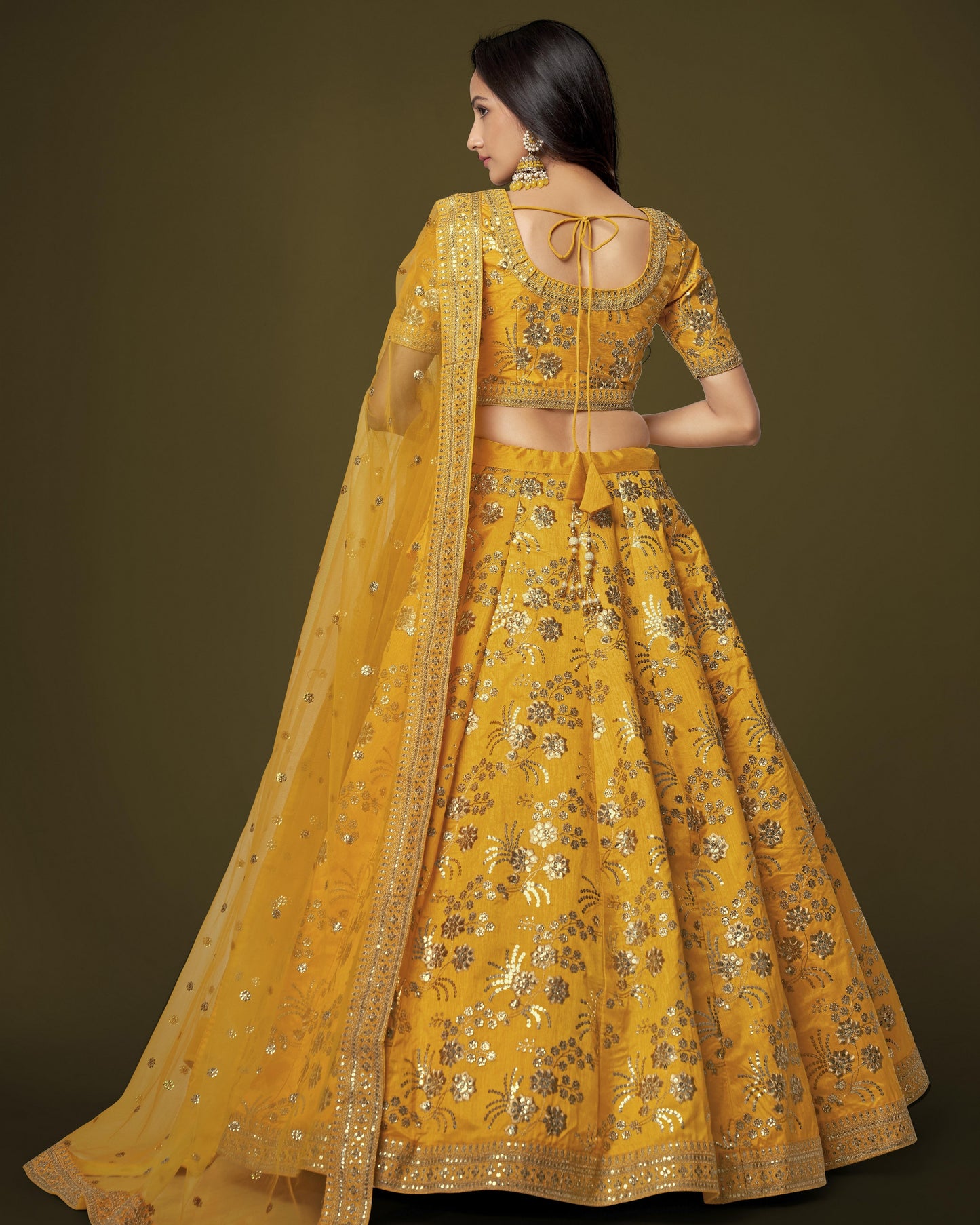 Woman wearing a yellow embroidered traditional outfit with a dark background