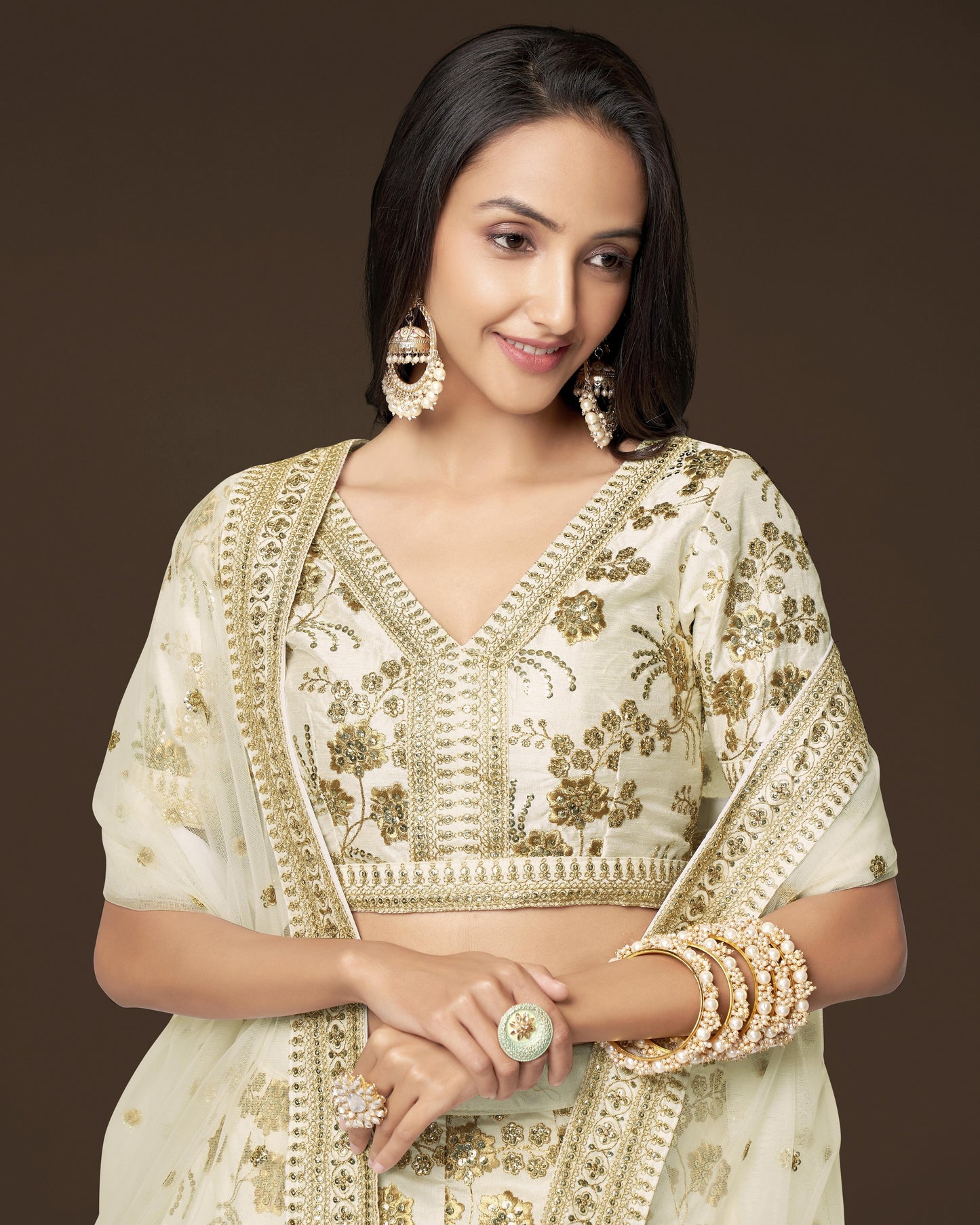 Woman wearing a traditional embroidered outfit with gold details on a brown background