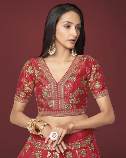 Woman wearing a red and gold embroidered traditional outfit on a maroon background