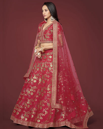 Woman wearing a red embroidered lehenga with gold details on a maroon background