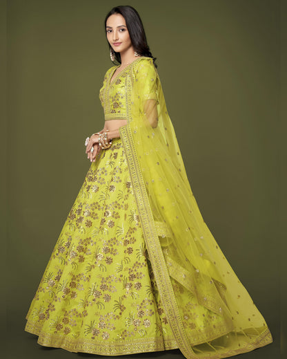 Woman wearing a bright yellow embroidered traditional outfit on a green background