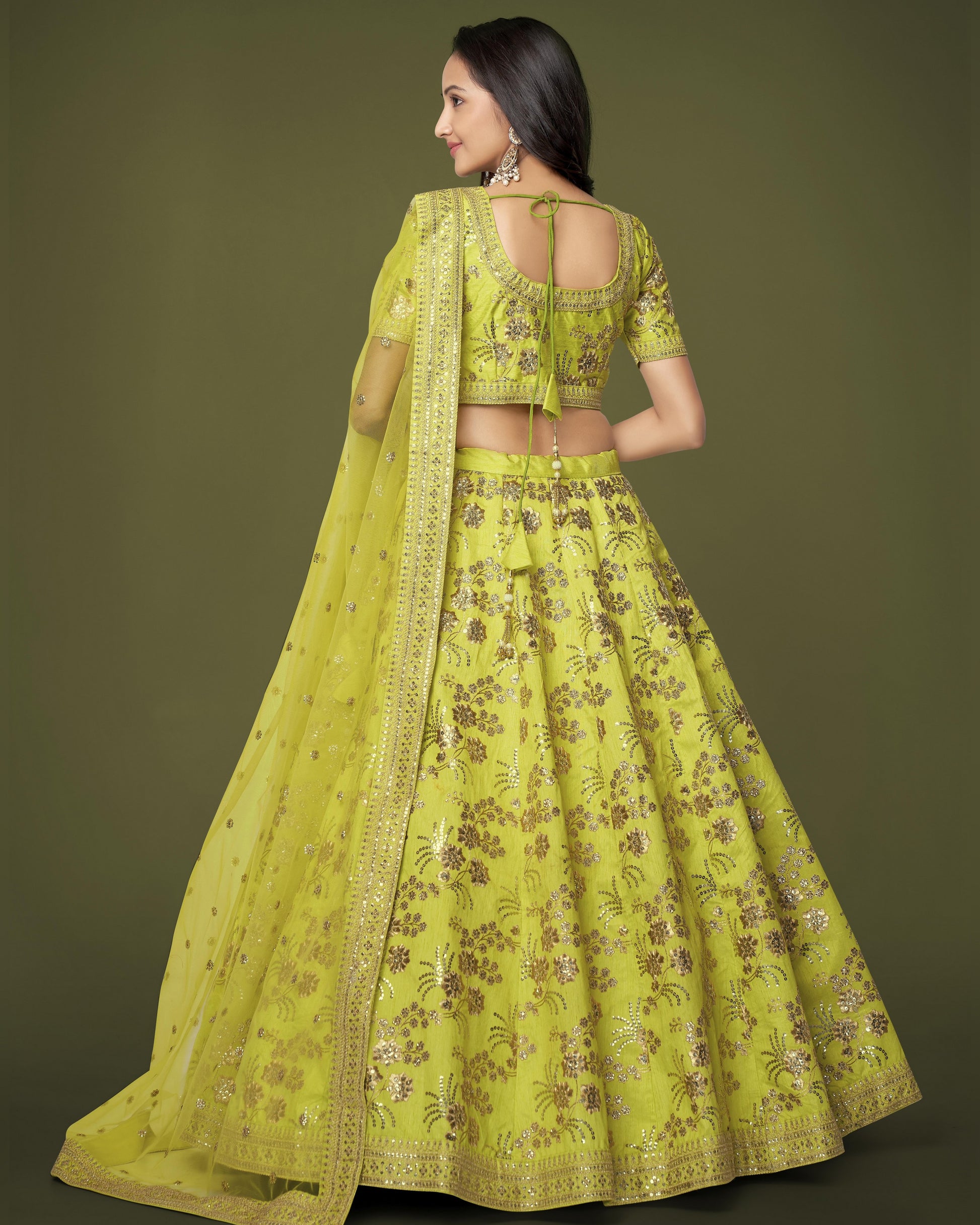 Woman wearing a bright yellow embroidered traditional outfit on a green background