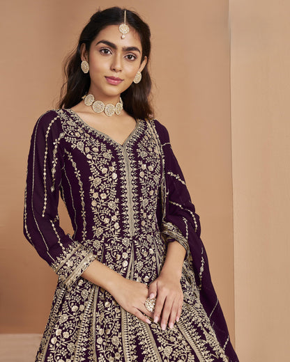 Woman wearing a purple and gold embroidered traditional outfit against a beige background